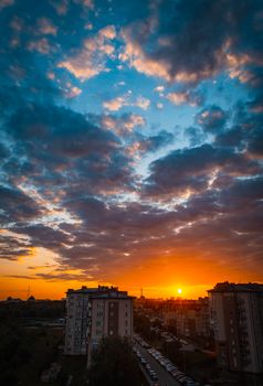 A vibrant sunset with dramatic clouds over a city skyline, creating a stunning evening scene.