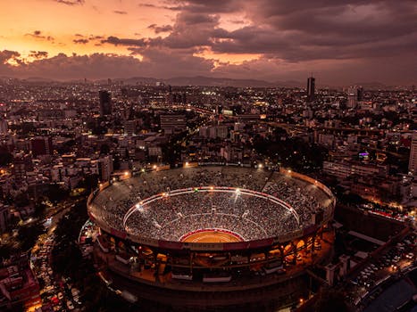 Stunning aerial shot of Mexico City's bullring and skyline at sunset, capturing vibrant urban life.