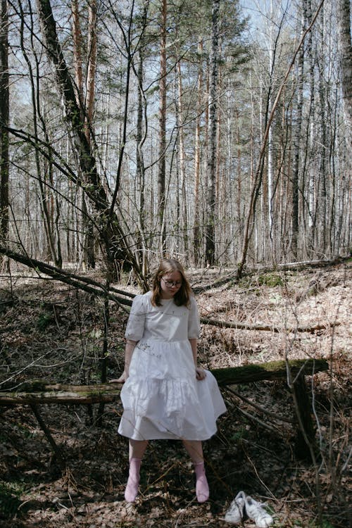 Woman in White Dress Sitting and Posing in Forest