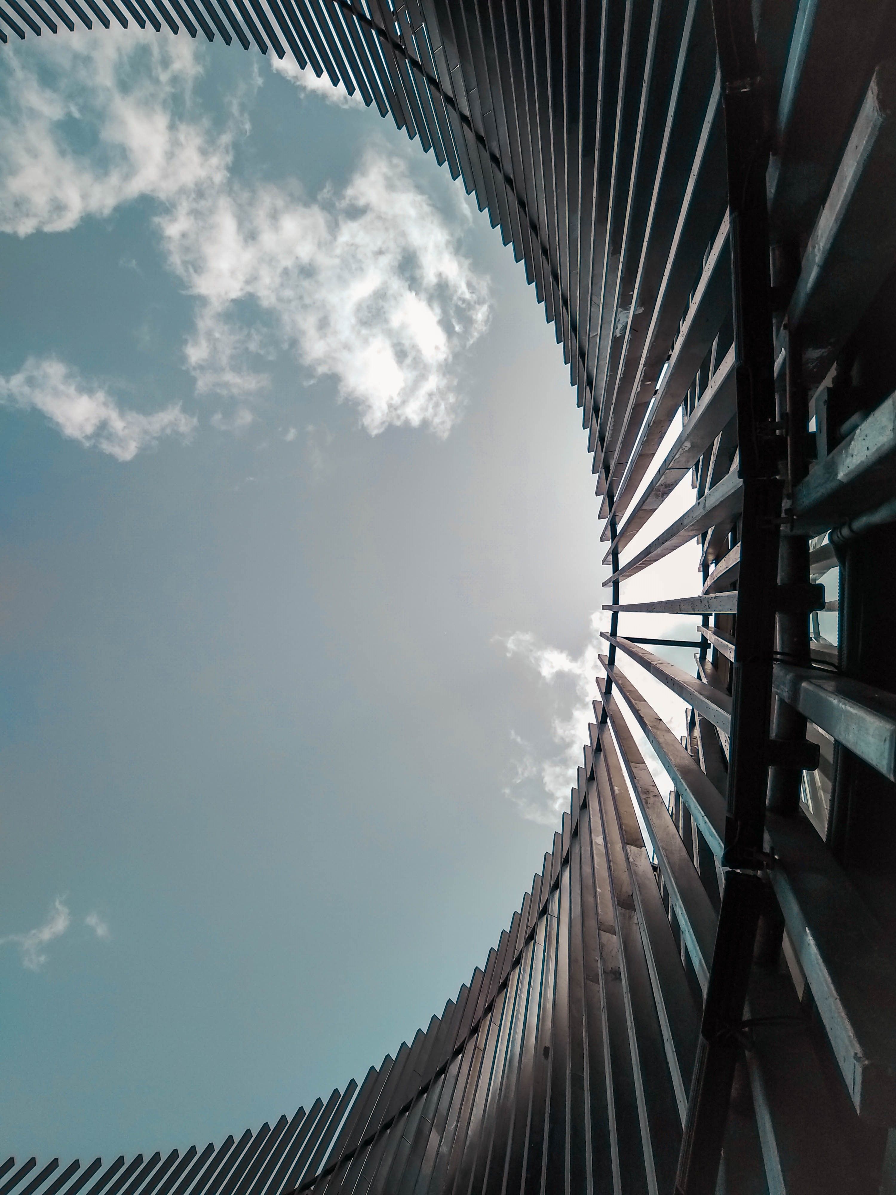 A Low Angle Shot of a Building Under the Gray Sky and White Clouds ...