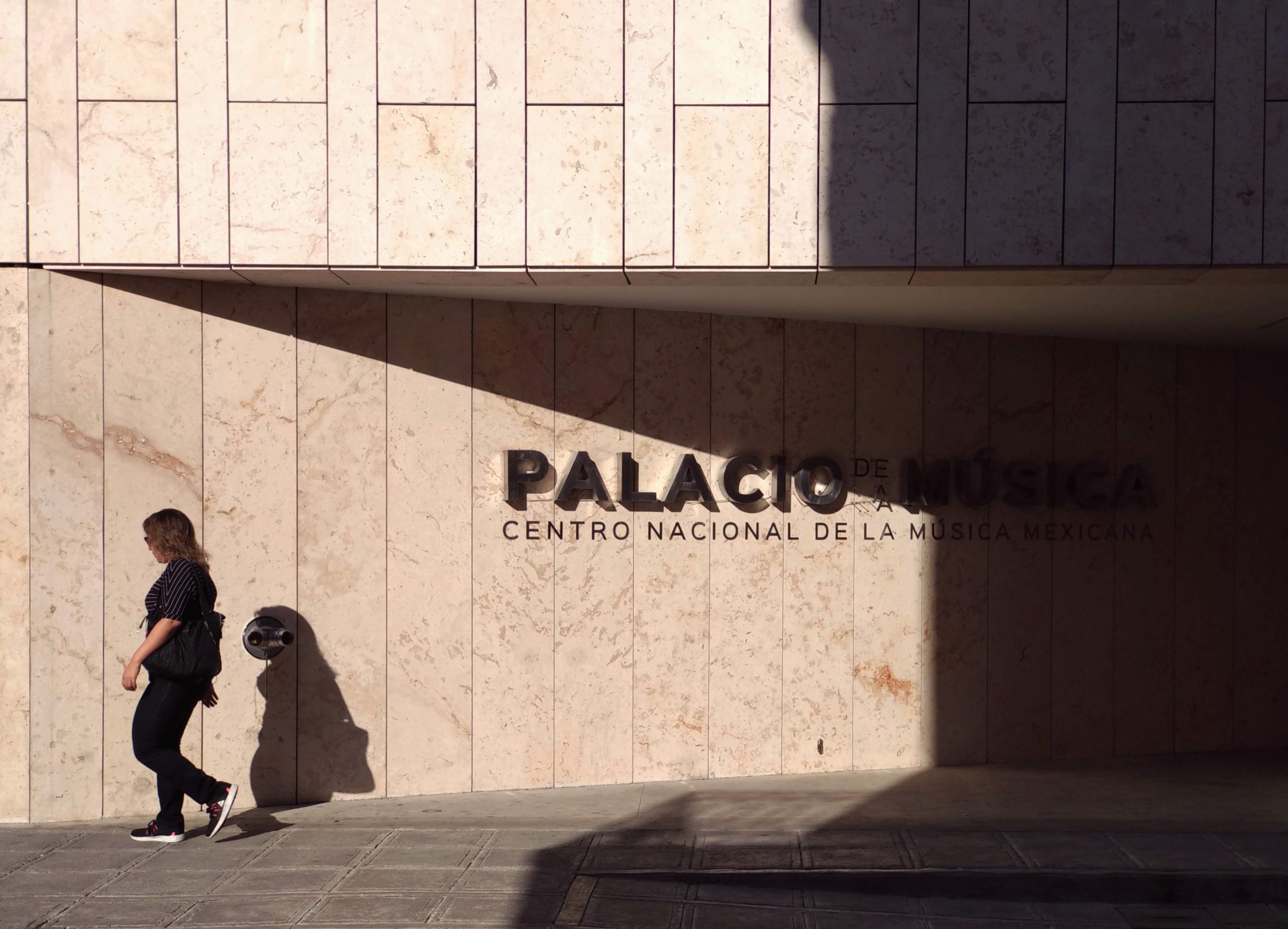 Facade of Palacio de la Música, Mérida, with a person walking past on a sunny day.