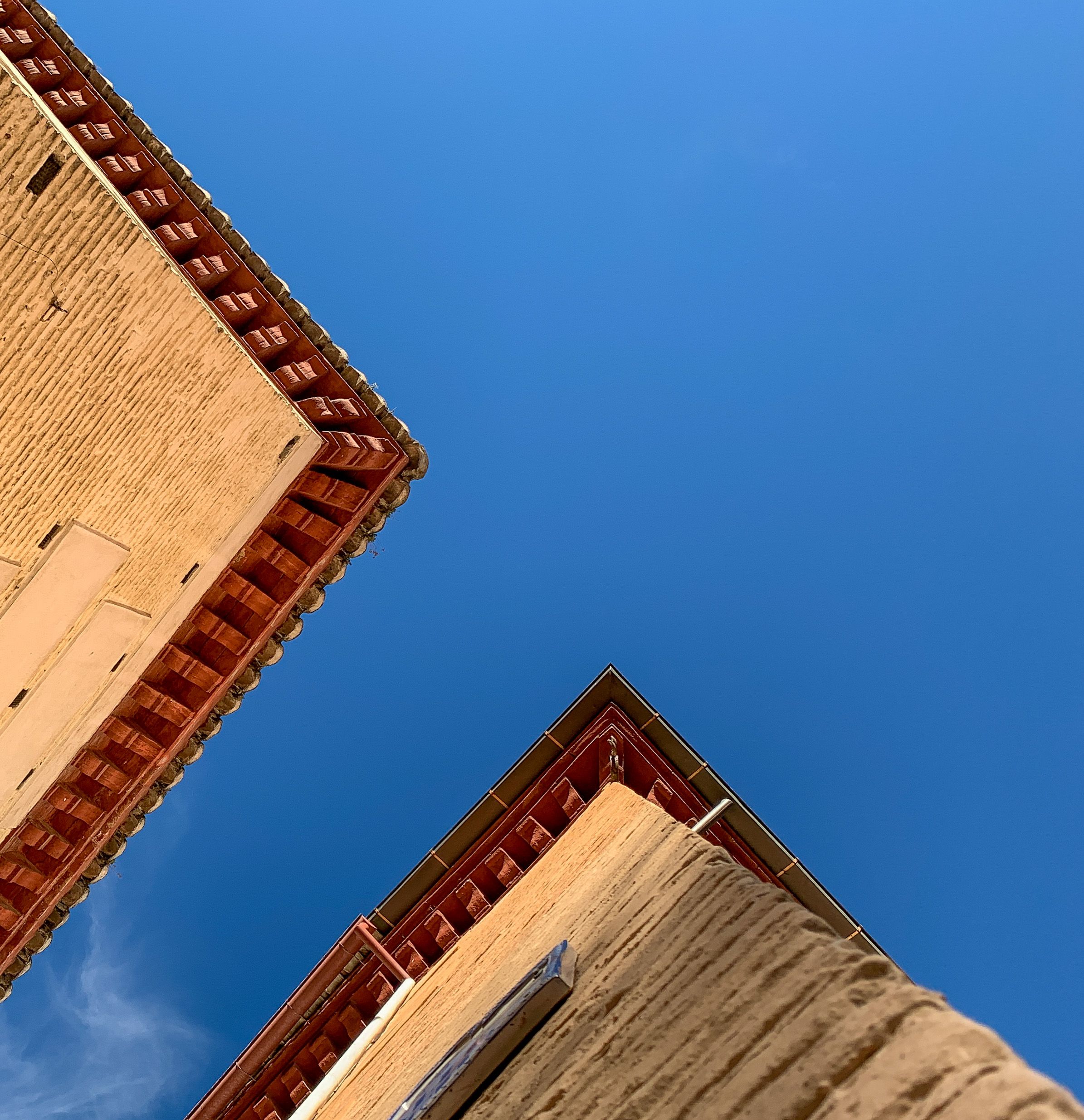 Captivating low angle view of traditional Spanish buildings against a vibrant blue sky in Granada.