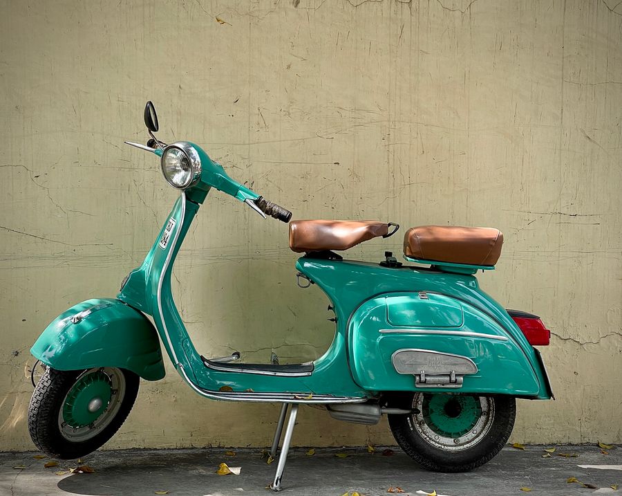 Teal Velda scooter parked against a plain wall — photo by Nishant Aneja on Pexels