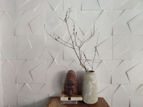 Minimalist decor featuring a textured vase and tribal figurine against a geometric white wall.