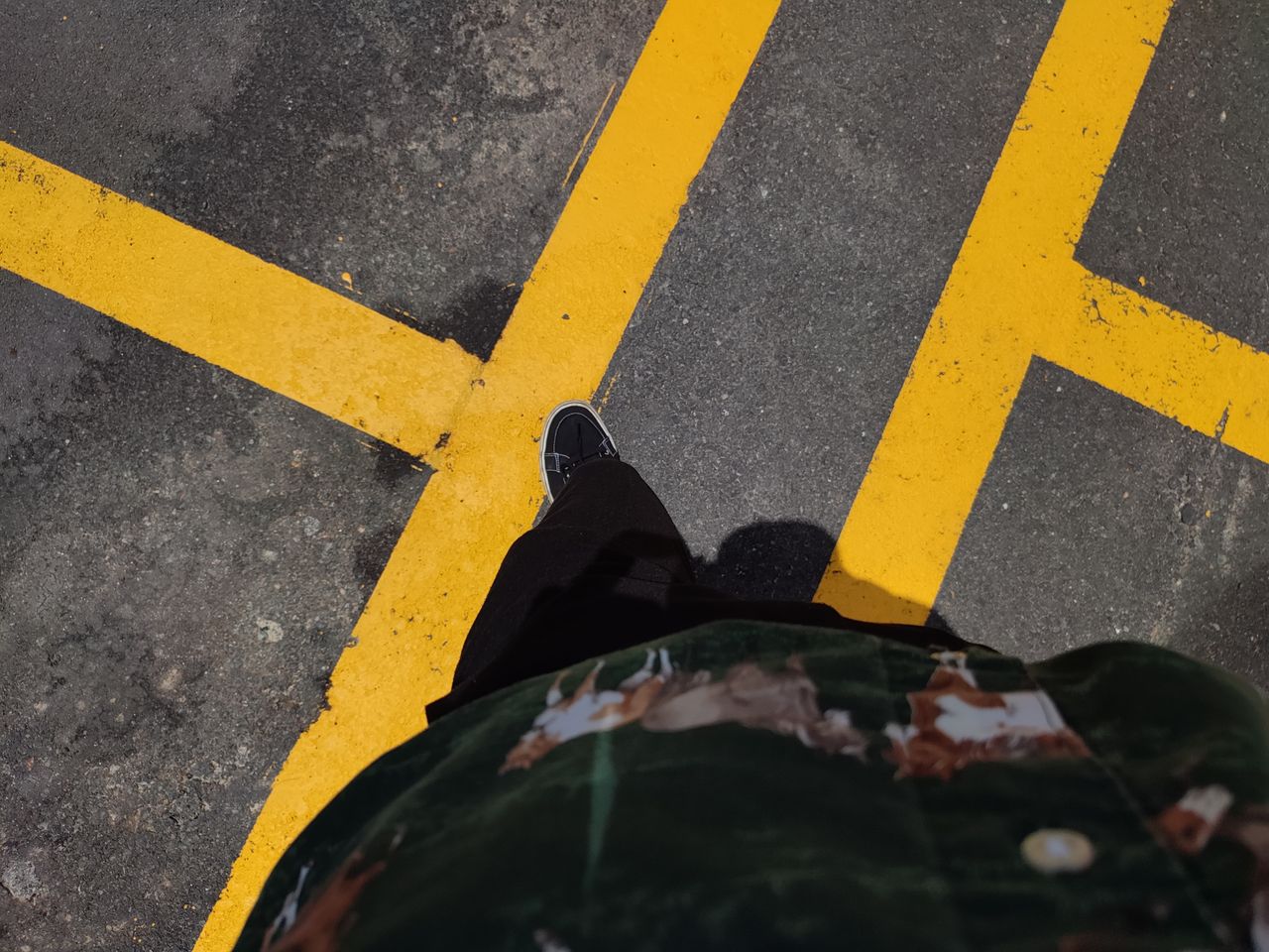 person standing on marked asphalt with visible yellow lines high angle