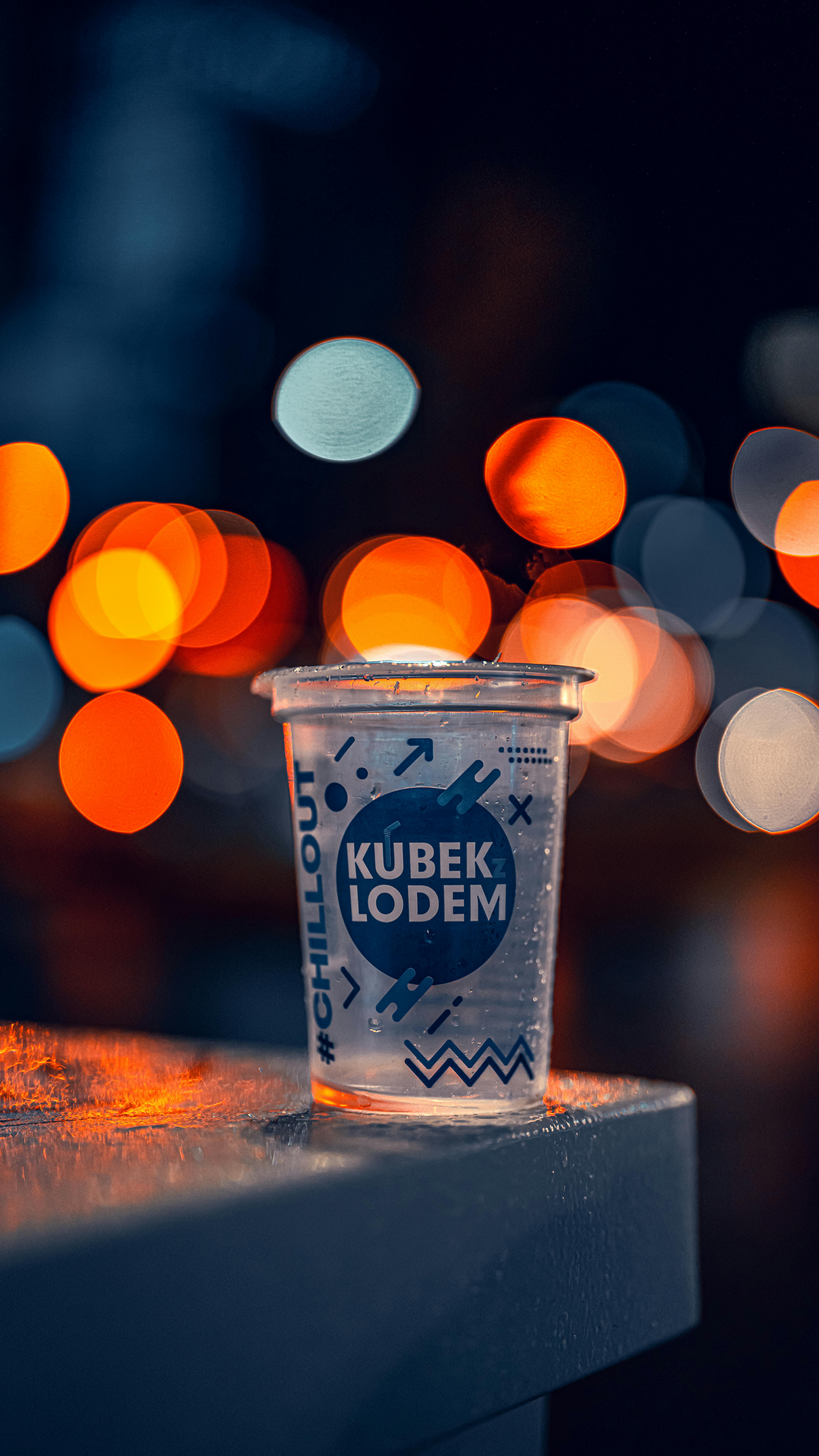 A plastic cup with vibrant bokeh lights in the background, taken in Warsaw at night.