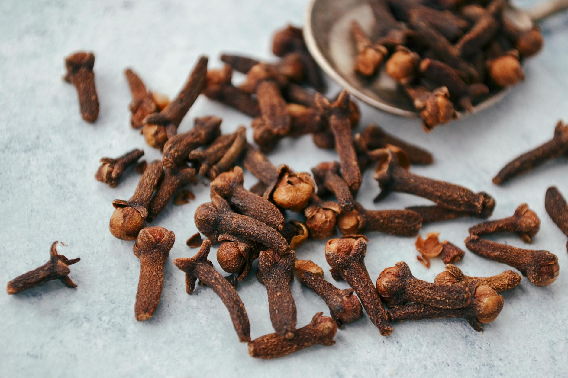 https://www.pexels.com/photo/close-up-of-cloves-scattered-on-gray-surface-12142752/