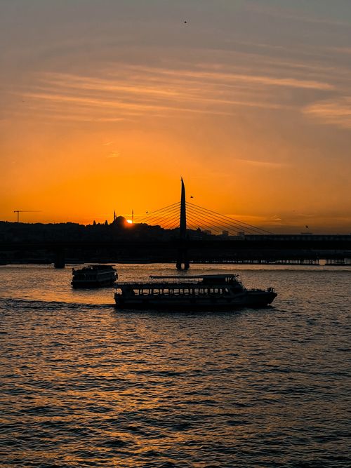 Free Silhouetted boats and bridge at sunset on the Bosphorus Strait in Istanbul, Turkey. Stock Photo