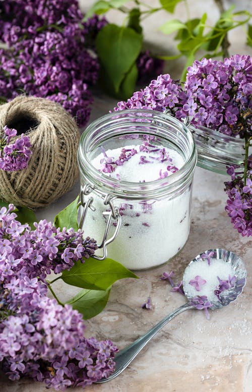Close-up Photo of Sugar in a Glass Jar with Lilac Flowers 