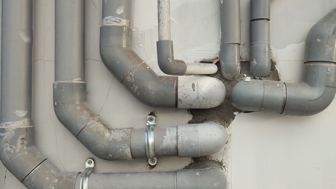 Exposed pipes running along the outside wall of a building