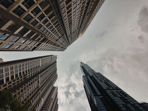 Free Low-angle view of modern skyscrapers reaching into cloudy skies, highlighting urban architecture. Stock Photo