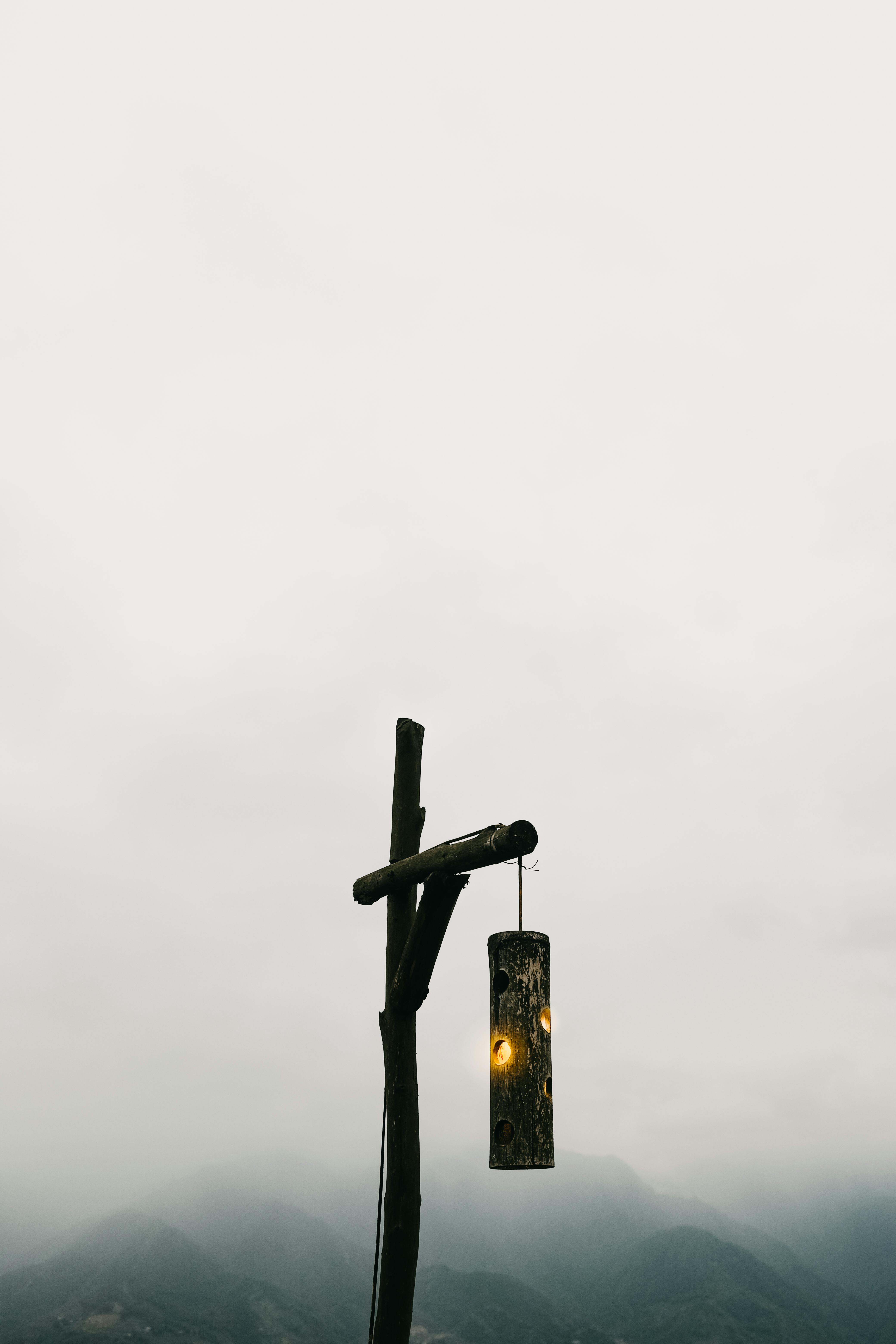 A rustic wooden lamp post set against a misty landscape, creating a serene and tranquil atmosphere.