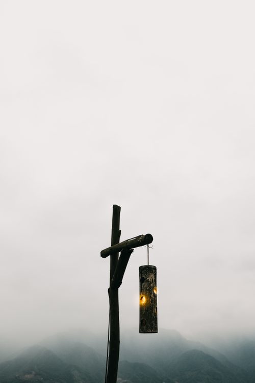 Free A rustic wooden lamp post set against a misty landscape, creating a serene and tranquil atmosphere. Stock Photo