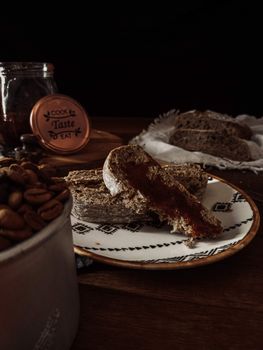 A close-up of rustic bread with jam and coffee beans on a wooden table.