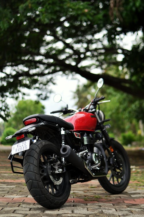 A Red and Black Motorcycle Parked Under the Tree 