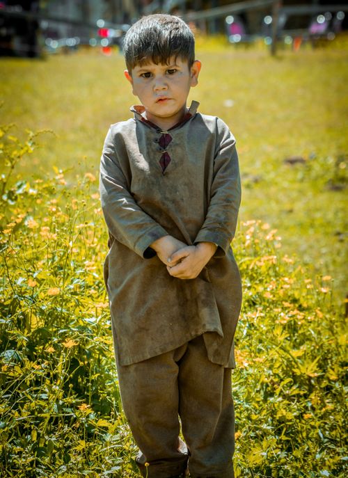 Free A young boy stands in a field in Arang Kel, wearing traditional attire surrounded by flowers. Stock Photo