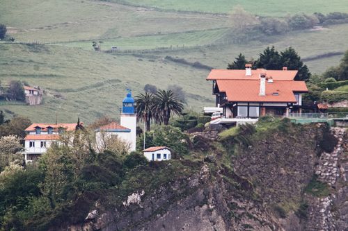 Free A picturesque view of coastal villas on a cliffside in PV, Spain, surrounded by lush greenery. Stock Photo