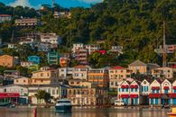 Captivating view of a vibrant hillside town in Grenada, featuring colorful buildings and a calm harbor.