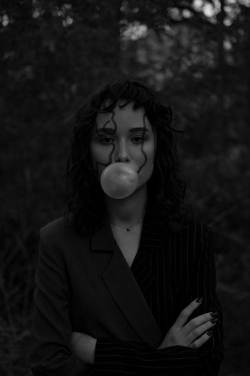 Grayscale Photo of a Woman Chewing a Gum