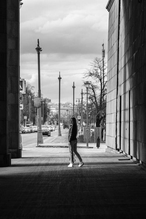 Grayscale Photo of Woman Standing on the Sidewalk
