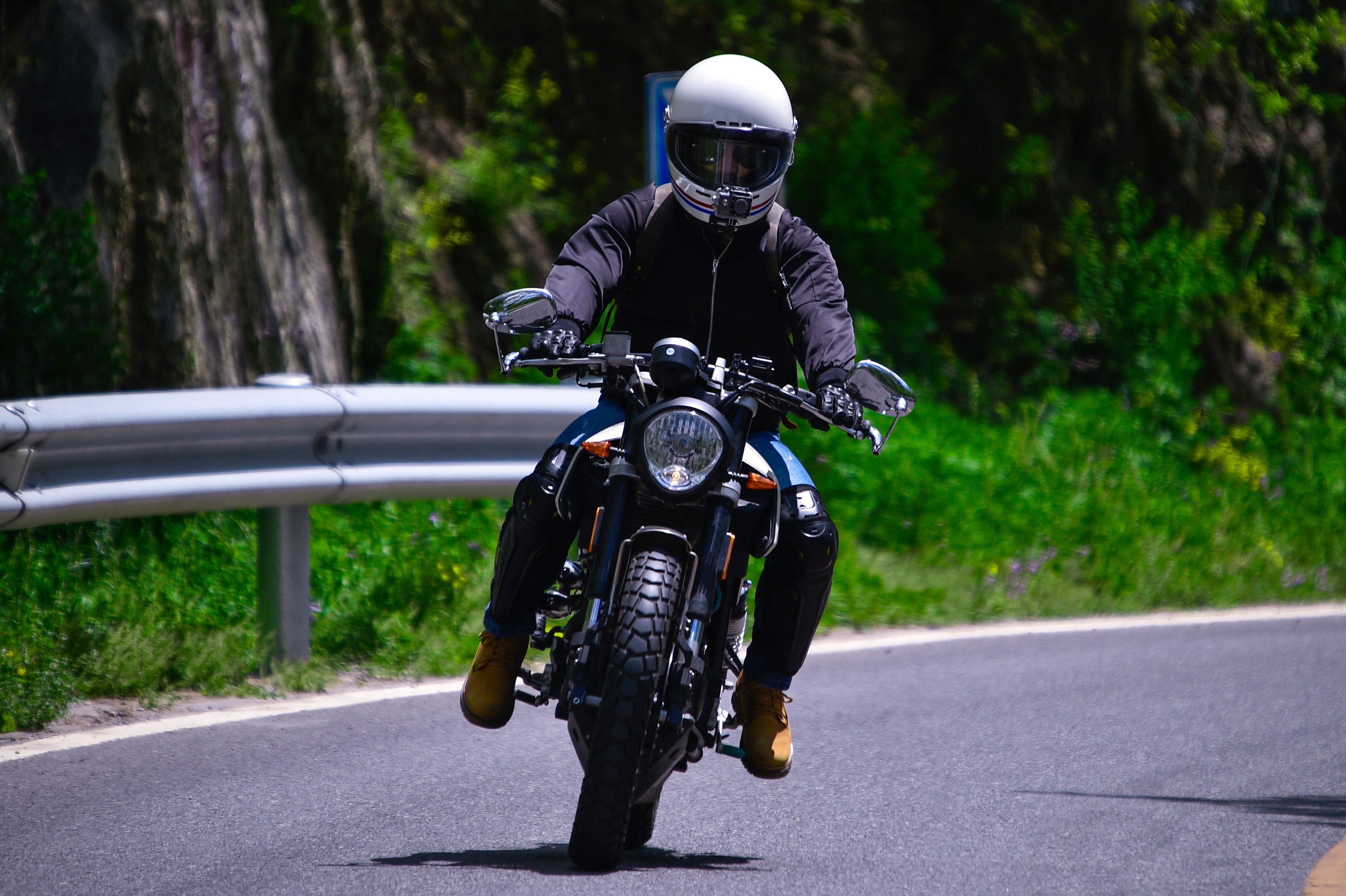 A motorcyclist skillfully maneuvers a bike on a picturesque winding road, wearing a safety helmet.