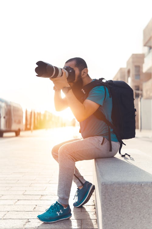 無料 デジタル一眼レフカメラを使用して写真を撮るバックパックを運ぶ男 写真素材