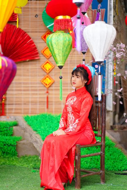 Graceful woman in traditional Asian attire amidst vibrant cultural decorations.