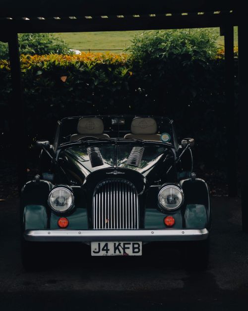 Free Vintage Morgan car with shiny finish parked under a shelter, showcasing classic design. Stock Photo