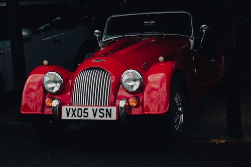 Free A classic red convertible car parked in dim lighting, showcasing vintage elegance. Stock Photo