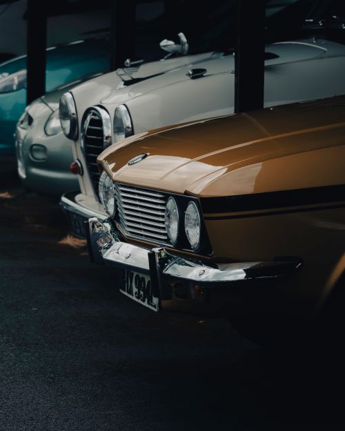 Free Three classic vintage cars parked indoors, showcasing elegant design and shiny exteriors. Stock Photo