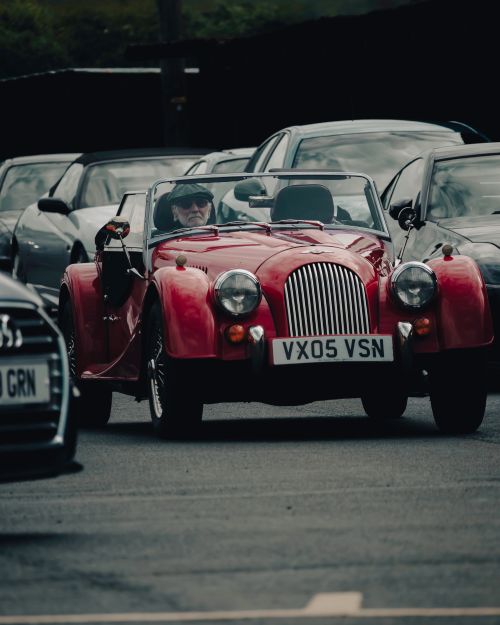 Free Classic red Morgan convertible car parked among modern automobiles in a city parking lot. Stock Photo