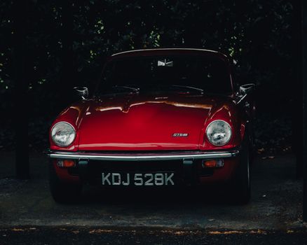 Front view of a shiny red vintage sports car parked outdoors. Classic design.
