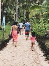 People Walking on Dirt Road Near Green Palm Trees