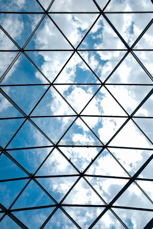 View of White Clouds and Blue Sky from a Roof Glass