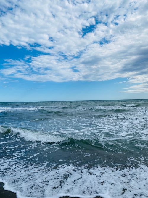 Free Captivating seascape with waves crashing on the shore under a dramatic cloudy sky. Stock Photo
