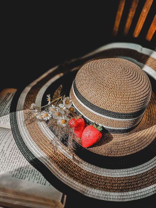 Free Aesthetic still life with a straw hat, fresh strawberries, and daisies. Stock Photo