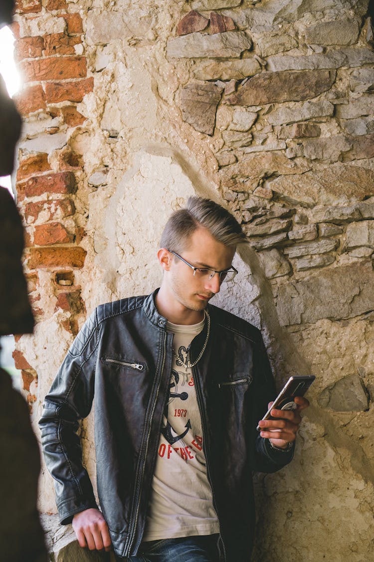 A Man In Black Leather Jacket Using His Mobile Phone