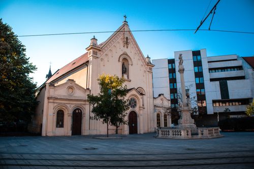 Free Gothic-style church facade with adjacent modern architecture under a clear blue sky. Stock Photo