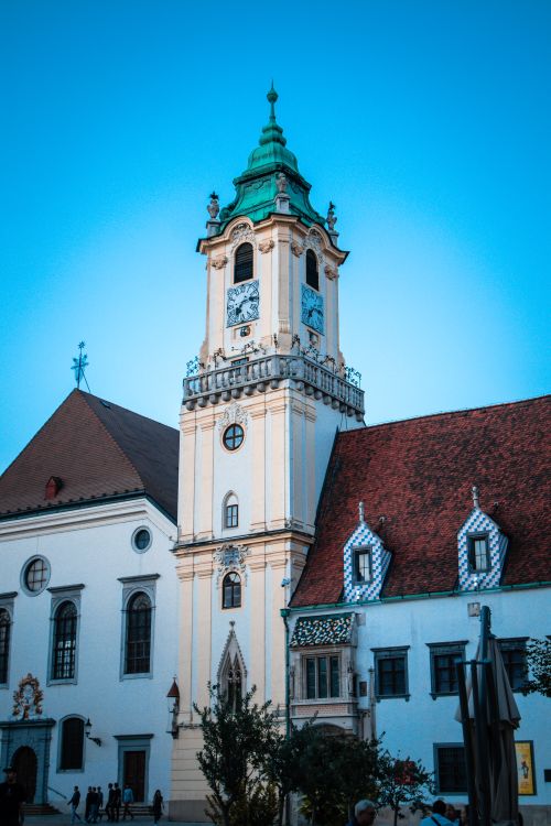 Free A picturesque view of a historic church tower with architectural details against a clear blue sky. Stock Photo