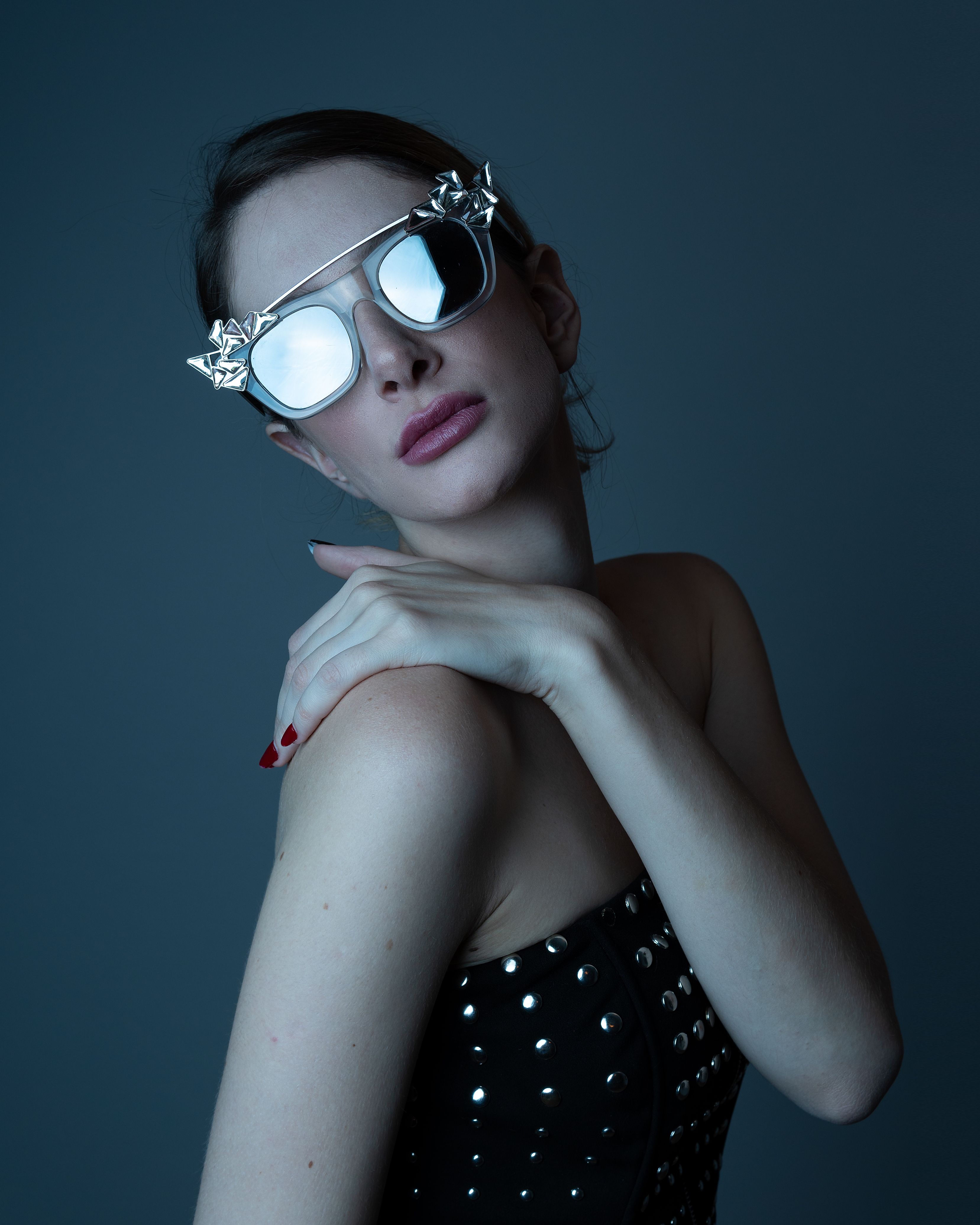 Elegant portrait of a woman wearing reflective sunglasses and a studded tube top. Fashion statement.
