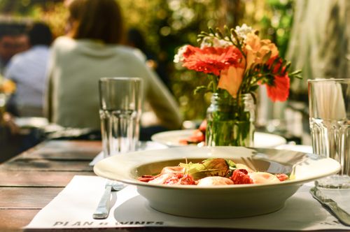 Free Delight in a cozy outdoor dining scene featuring a beautifully plated pasta dish and floral arrangements. Stock Photo