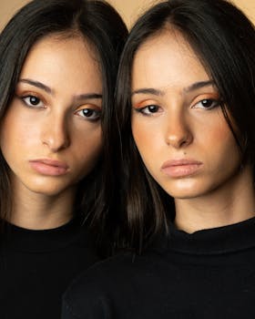 Close-up portrait of teenage twin sisters with neutral expressions.