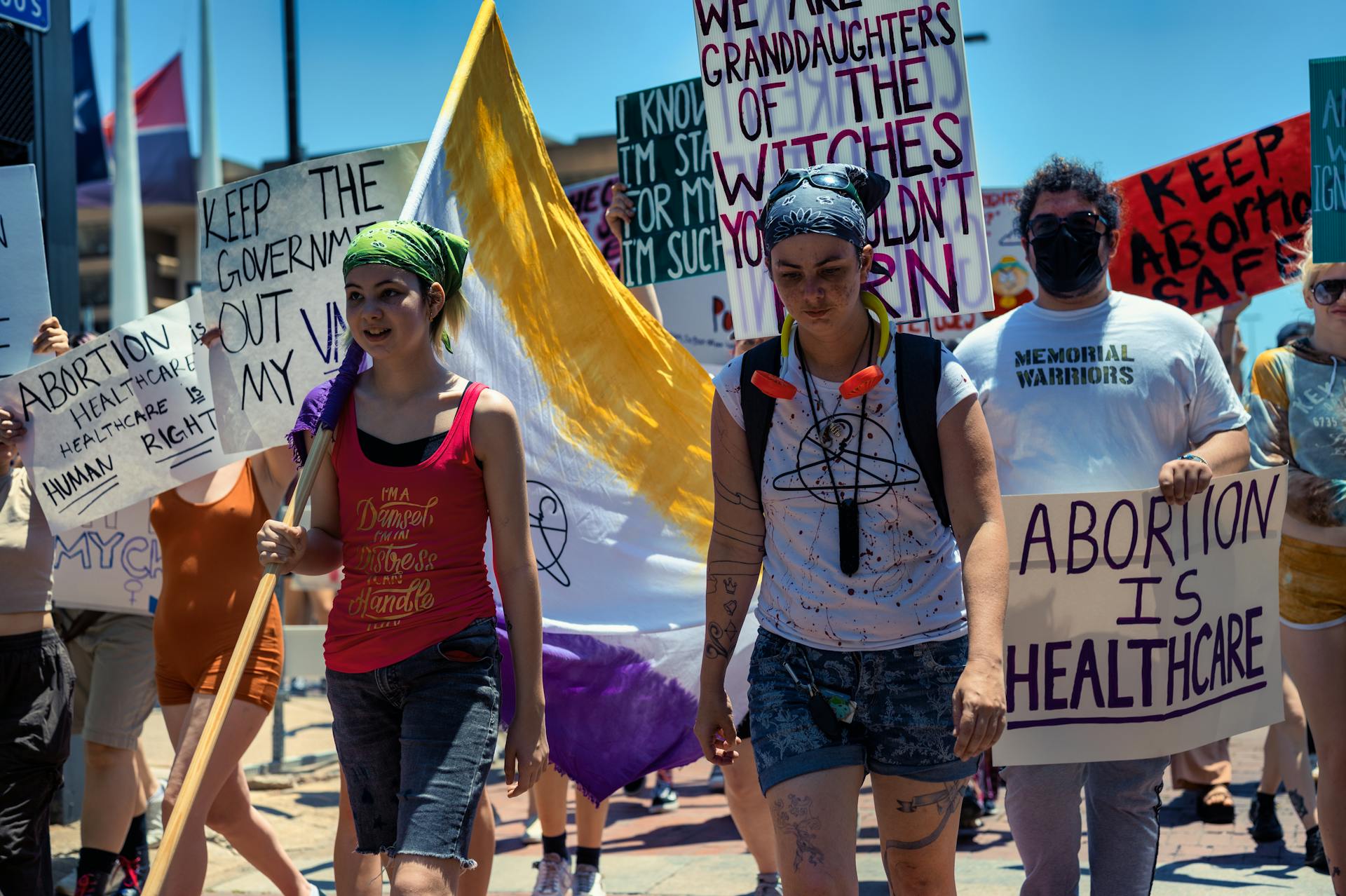 A diverse group of women and men protest for abortion rights, holding powerful placards.