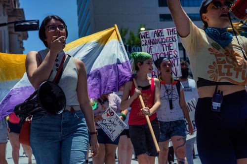 Free A group of women passionately protesting for women's rights with banners and flags in an urban setting. Stock Photo