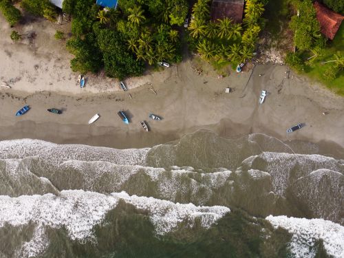 Free Aerial shot capturing a serene beach, boats, and lush greenery along the coast. Stock Photo