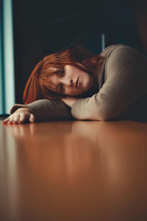 Free Redhead Girl Lying on Side on Brown Table Stock Photo