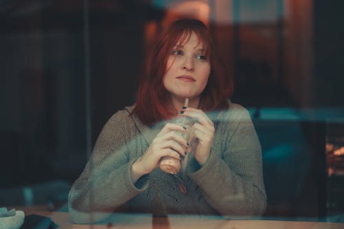 Redheaded Woman Behind Window Pane Drinking Juice 