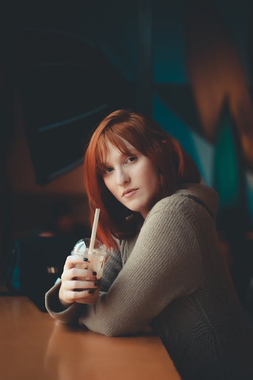 Free A Woman in a Sweater Holding a Beverage Stock Photo