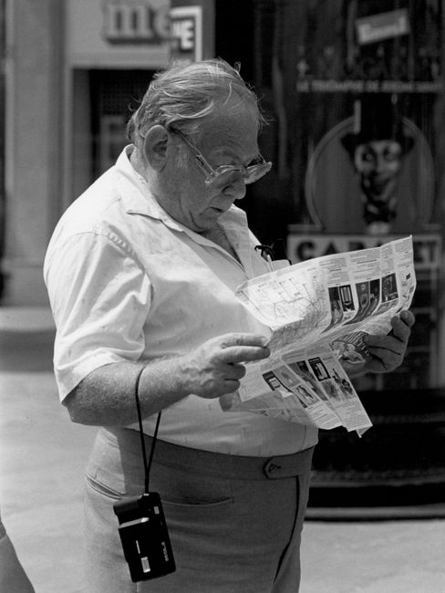 Elderly man reading a map in Paris, showcasing exploration and curiosity.