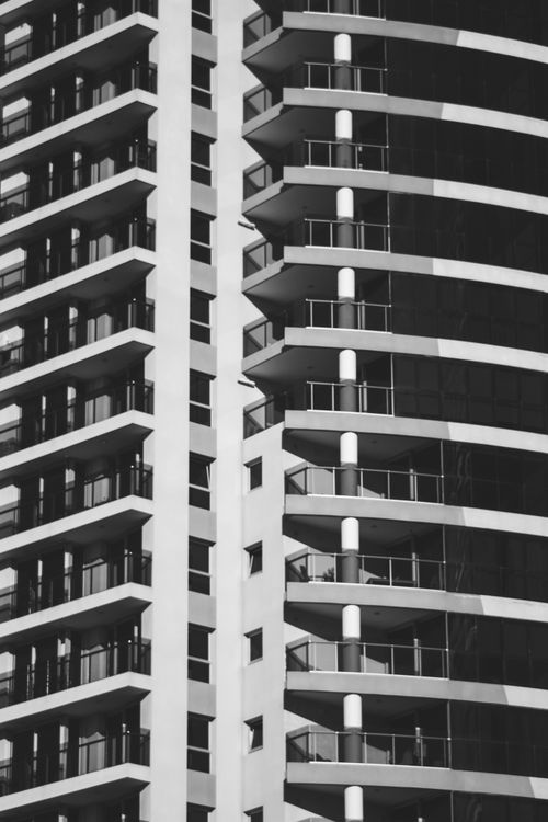 Free Black and white photo of a modern high-rise building facade showcasing sleek and curved architecture. Stock Photo